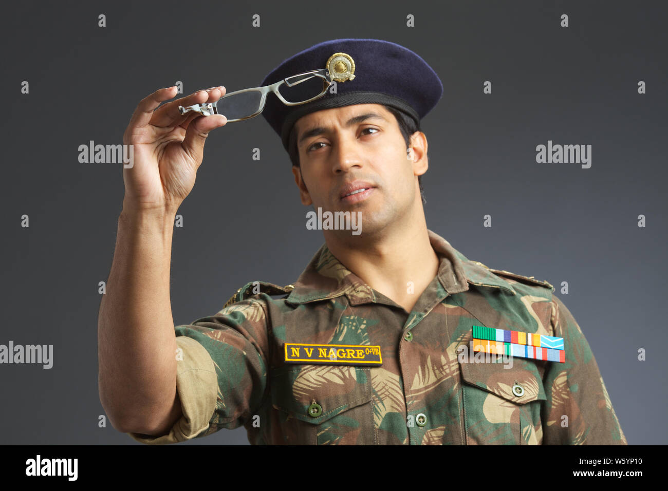 Armeesoldat, der eine Brille hält Stockfoto