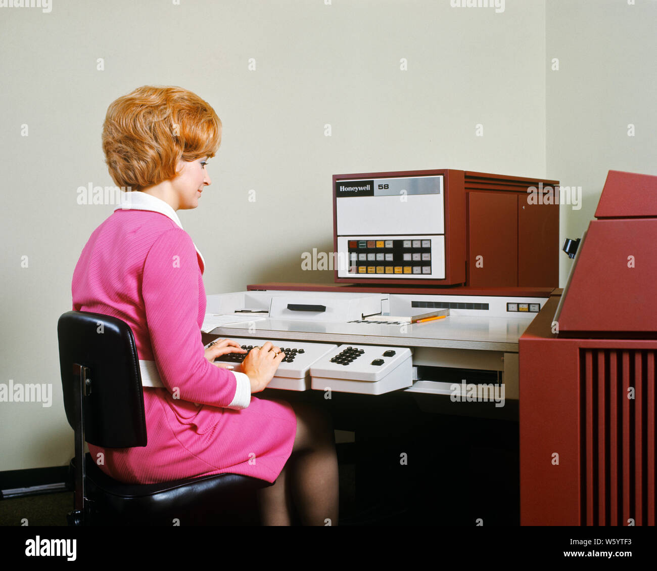 1970 s Frau sitzt AN DER TASTATUR BETRIEBSSYSTEM EINEM HONEYWELL 58 ELEKTRONISCHE DATENVERARBEITUNG MASCHINE-ko 565 HAR 001 HARS FÄHIGKEITEN, DIE FRISUR HAARE GEHÄNSELT INNOVATION BESCHÄFTIGUNG DER ARBEITSKRÄFTE BERUFE DATA ENTRY STILVOLLE DATENVERARBEITUNG MITARBEITER ELEKTRONISCHE JUNGEN ERWACHSENEN FRAU KAUKASISCHEN ETHNIE HAR 001 ARBEITENDEN ALTMODISCH Stockfoto