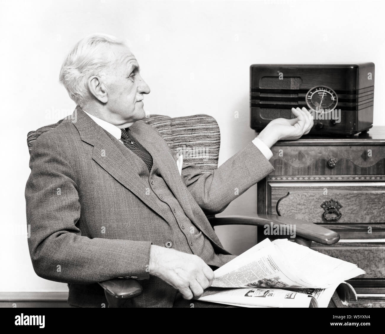 1940 s älterer Mann mit Anzug und Krawatte ZEITUNG IN SEINEM SCHOSS TUNING DAS RADIO eine DFÜ-r 12940 HAR 001 HARS DIAL RADIOS OLDSTERS ALTEN RUNDFUNK SEINE FREIZEIT AUDIO- UND GELEGENHEIT TUNING ÄLTESTEN VERBINDUNG STILVOLLE ÄLTERER MANN SCHWARZ UND WEISS KAUKASISCHEN ETHNIE HAR 001 ALTMODISCH Stockfoto