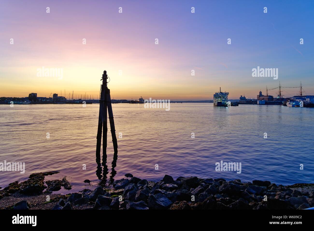 Ein Blick über den Hafen von Portsmouth in der Dämmerung gegen einen farbenprächtigen Sonnenuntergang und purple sky, Hampshire England Großbritannien Stockfoto