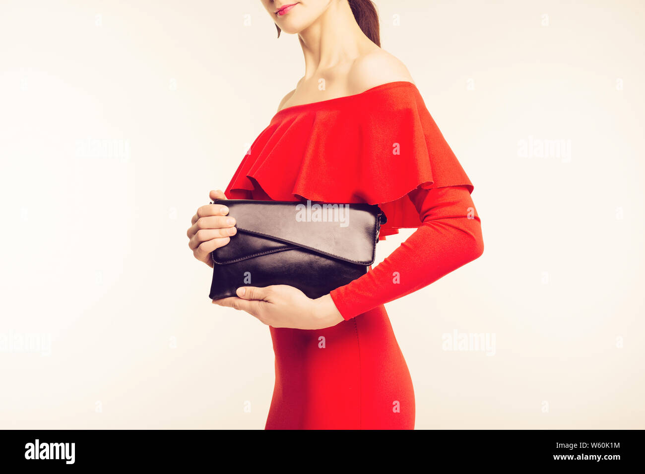 Die Frau im roten Kleid Holding elegante schwarze Handtasche Stockfoto