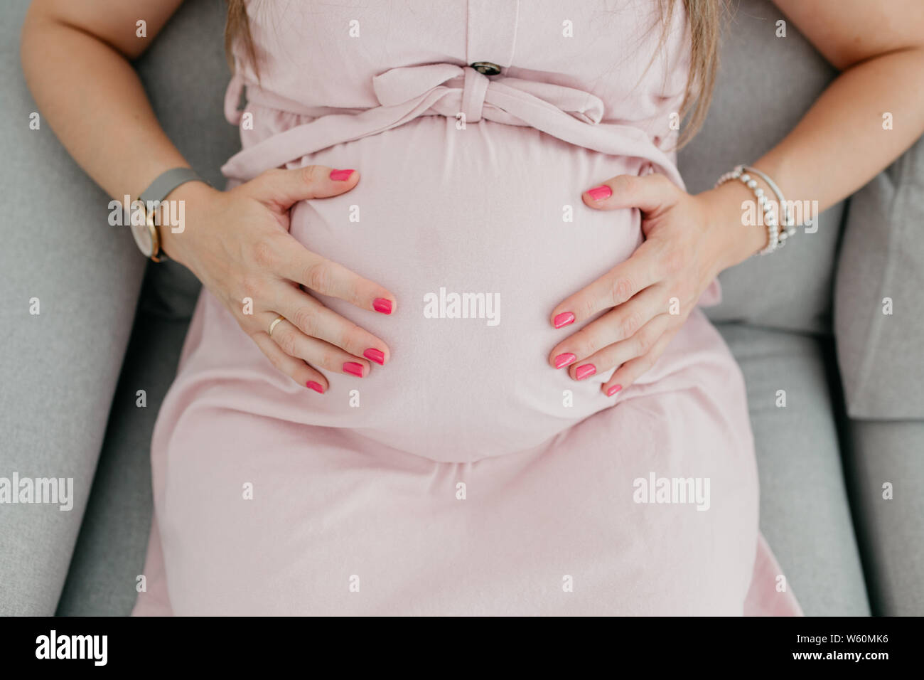 Nahaufnahme der Bauch einer schwangeren Frau mit einem rosa Kleid Stockfoto