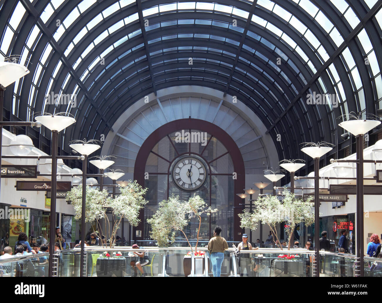 Eine Uhr ist am Ende einer gläsernen Korridor in einem Einkaufszentrum angezeigt. Stockfoto