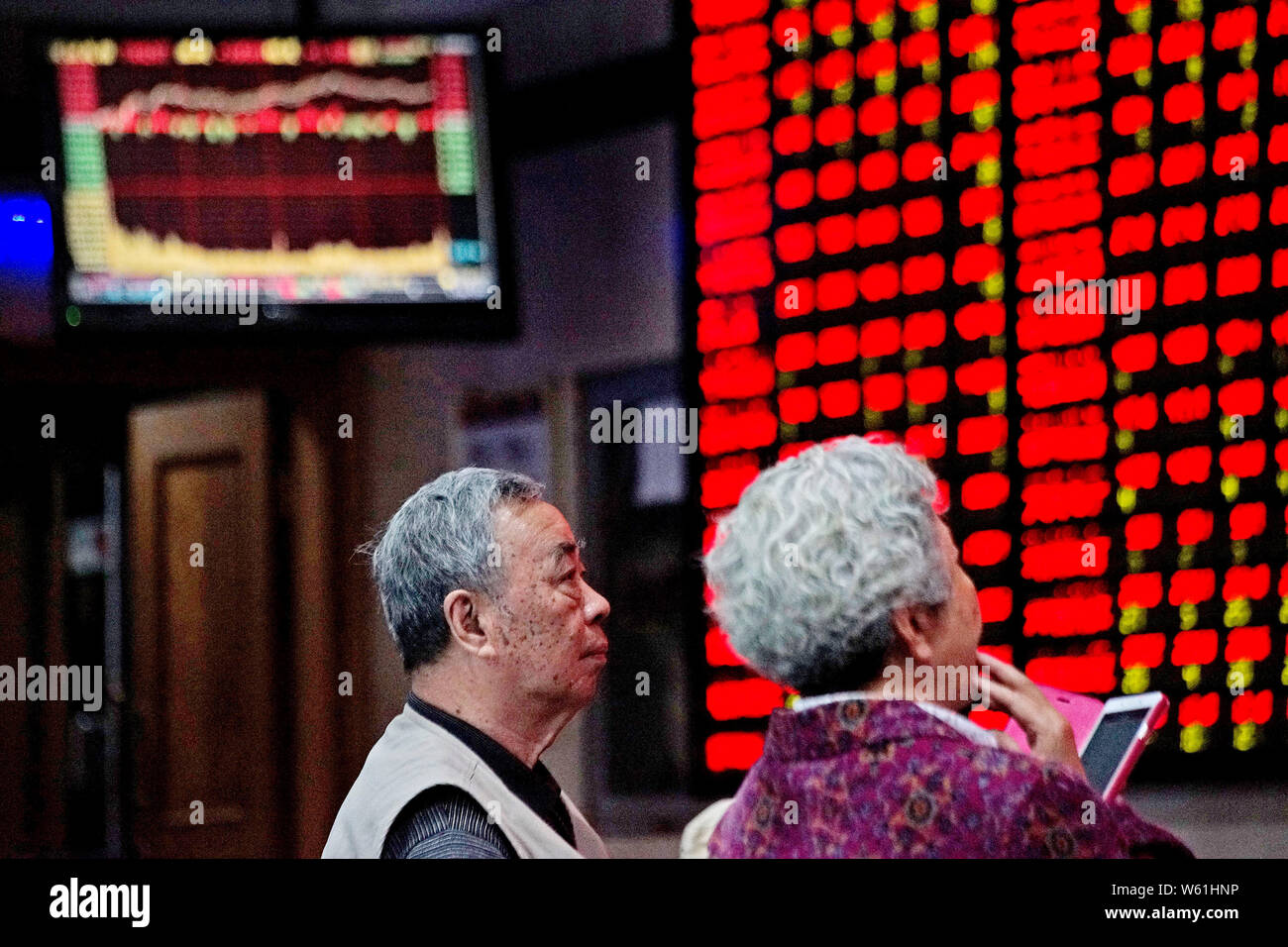 ------ Chinesische Investoren Blick auf eine elektronische Anzeige, die Preise der Aktien (rot für Preis steigt und grün für den Preis fallen) an einem Lager brokera Stockfoto