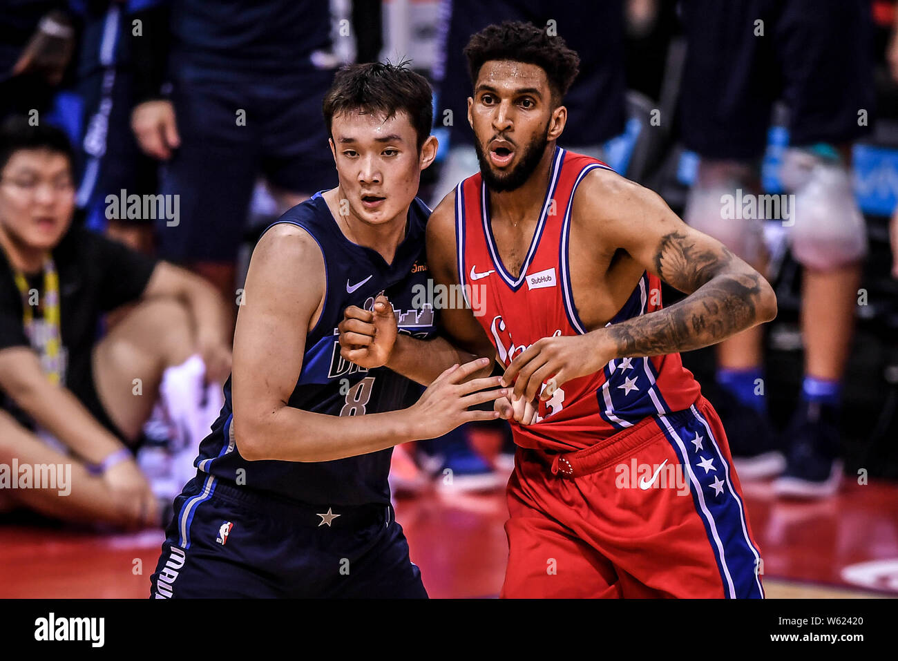 Ding Yanyuhang der Dallas Mavericks, Links, Herausforderungen Jona Bolden der Philadelphia 76ers bei der Shenzhen Spiel der NBA China Spiele in Shenzhen. Stockfoto