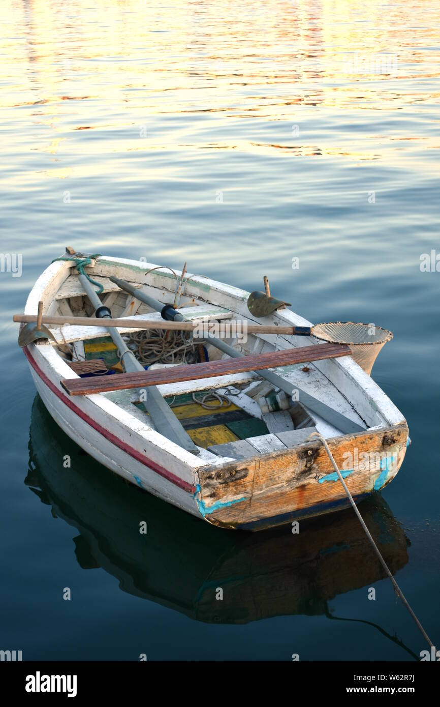 Vranjic, Kroatien - 20. Juli 2019: Kleine alte verwitterte Zerschlagene malerischen Holz- Rudern angeln Boot auf dem ruhigen Meer bei Sonnenuntergang widerspiegelt. Stockfoto