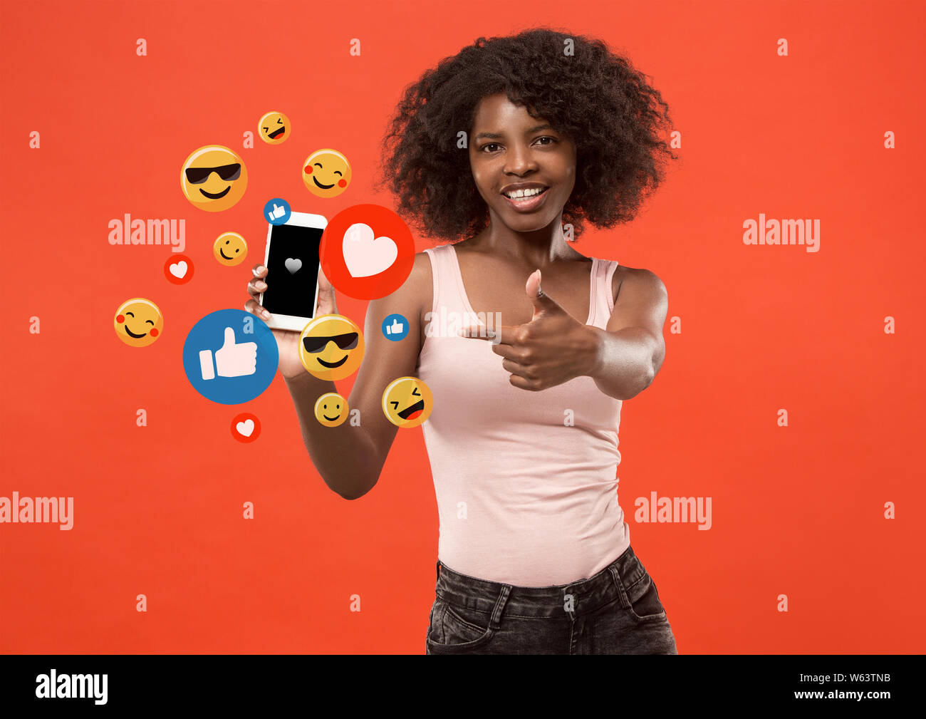 Social media Interaktionen auf Handy. Internet digital Marketing, Chatten, Kommentieren, Sympathie. Lächeln und Symbole über den Bildschirm des Smartphones, mit denen die junge Frau auf dem Roten studio Hintergrund. Stockfoto