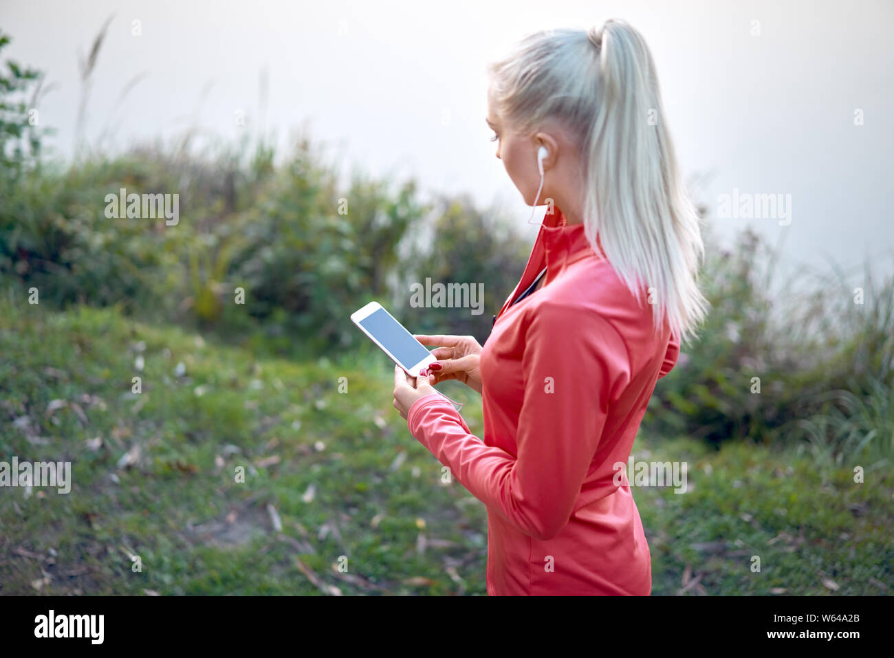 Läuferin in Park einrichten Musik auf Ihrem Handy Stockfoto