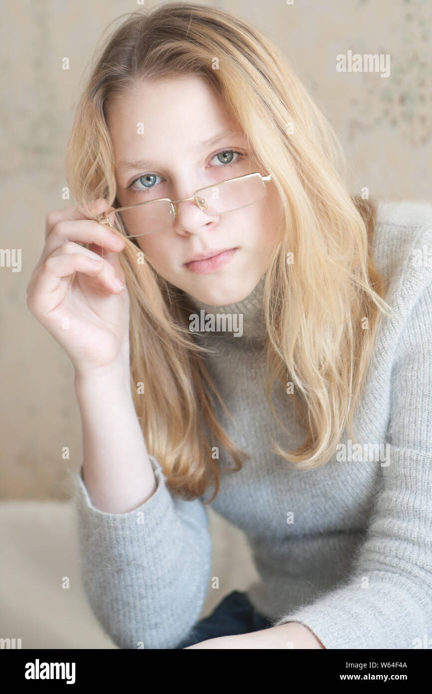 Junge Mädchen in Gläsern mit langen blonden Haaren sieht in die Kamera Stockfoto