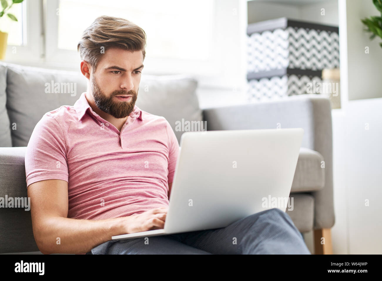 Betonte Mann mit Laptop zu Hause eingeben Nachricht Stockfoto