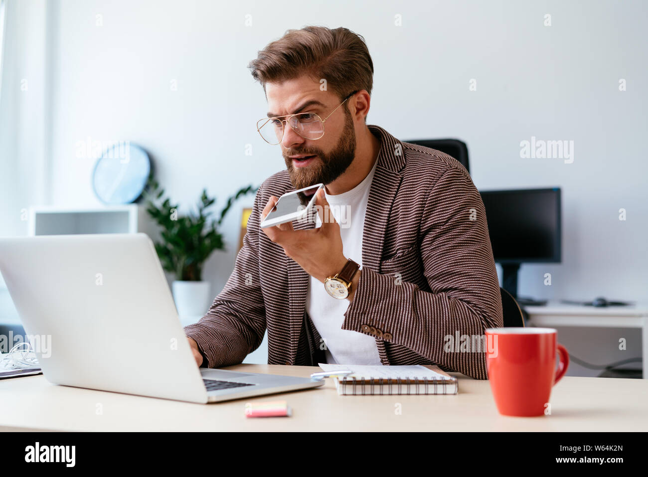 Junge startup Geschäftsmann am Telefon sprechen und Arbeiten am Laptop in modernen Büro Stockfoto