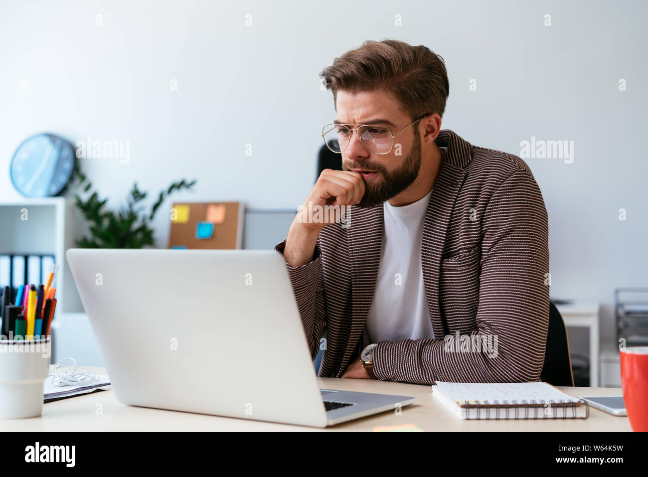 Schöner Mann sitzt im Home Office und Laptop betonte Stockfoto