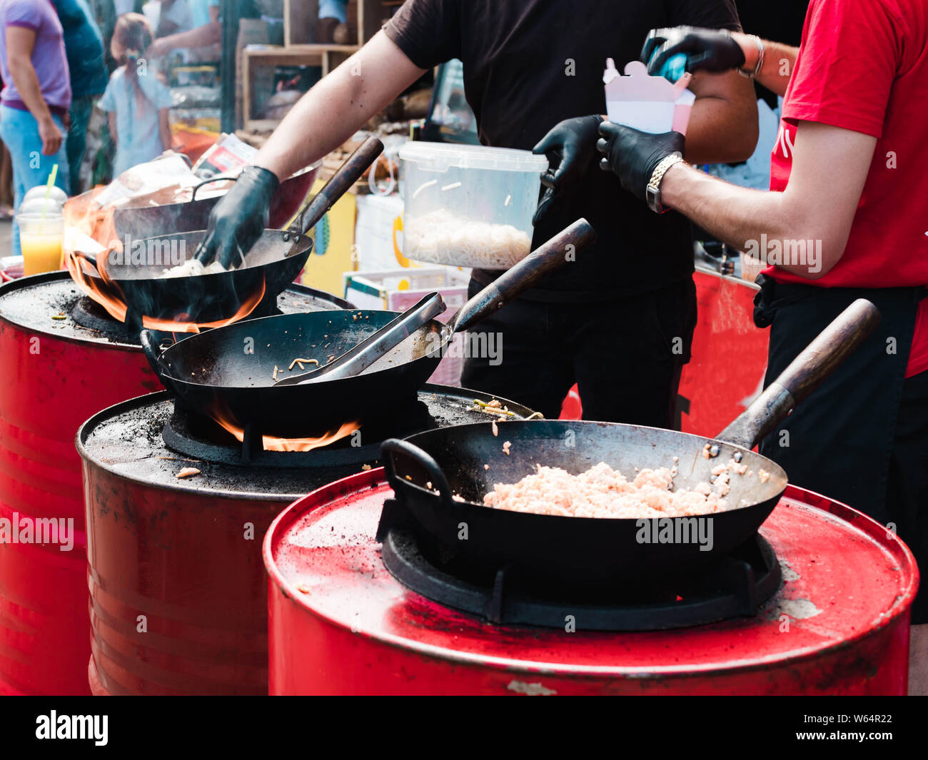 Kochen in Pfannen bei einem Straßenfest, Feuer mit roten Fässer. Stockfoto