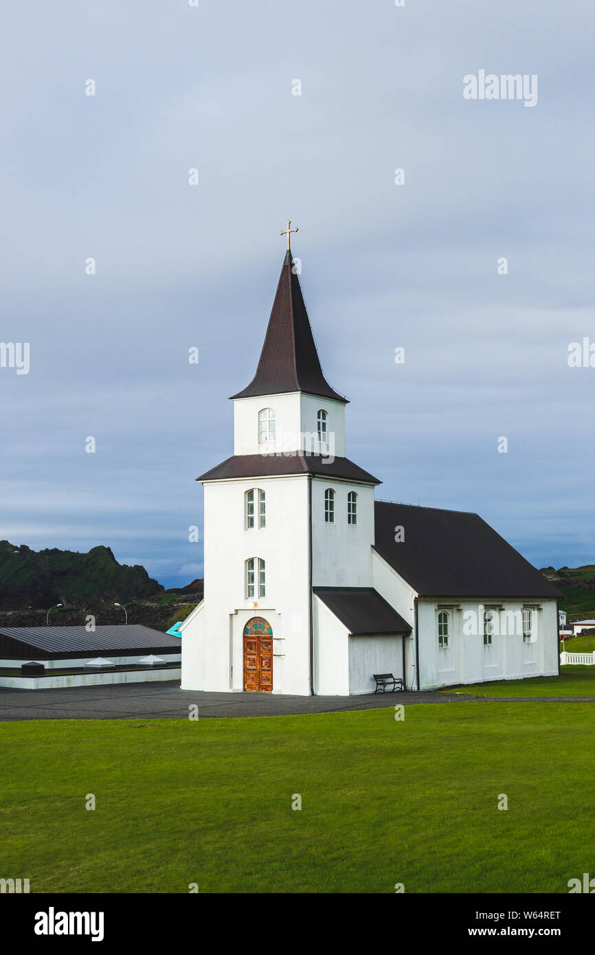 Kirche mit schwarzem Dach, weißen Wänden in traditionellen nordischen minimalistischen Stil auf Vestmannaeyjar Insel Heimaey in Island. Einfache Architektur, Grün Stockfoto