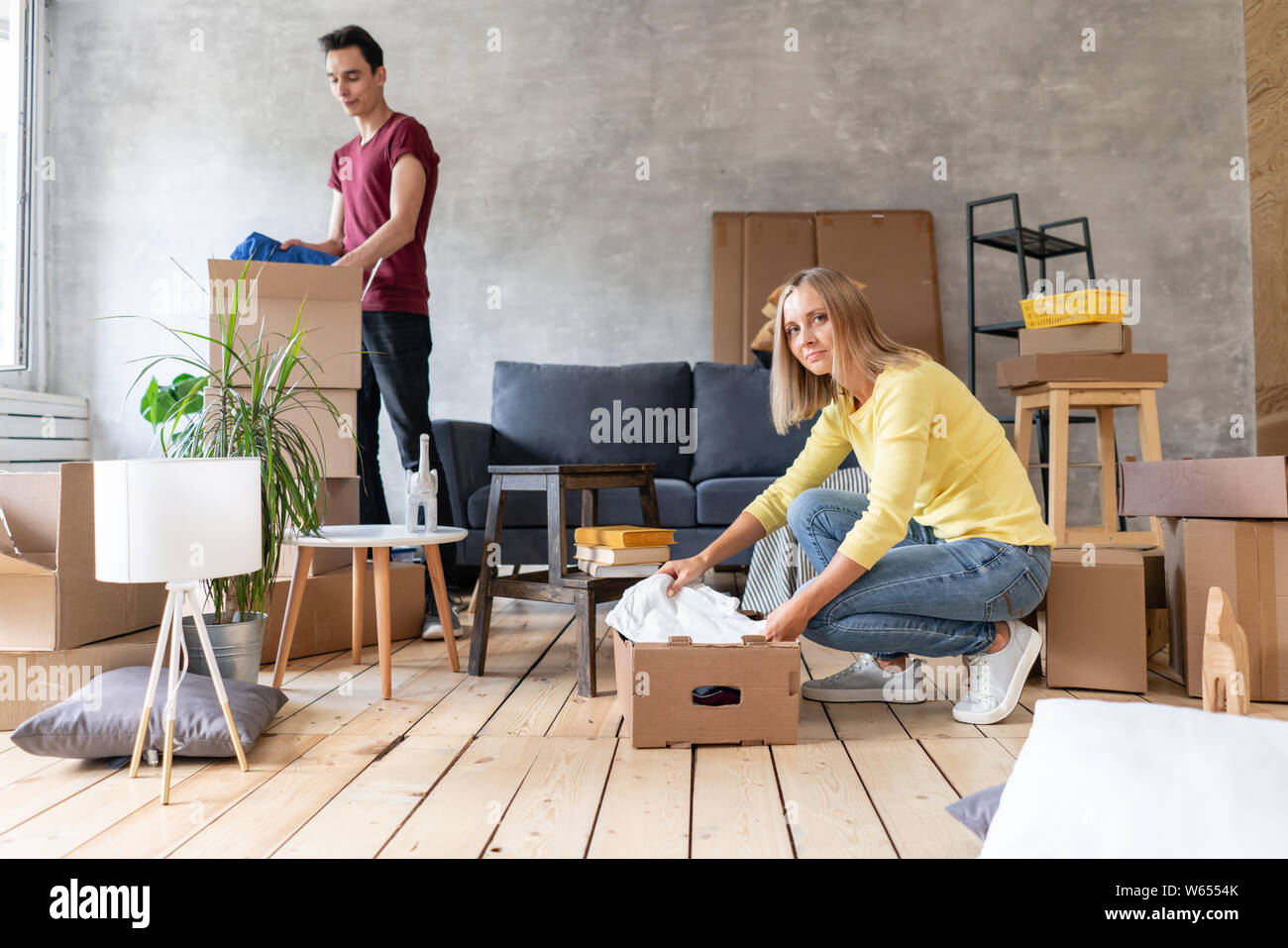 Glücklich lächelnde Paar Umzug in ein neues Haus und Auspacken der Kartons Kartons, Umzug und Renovierung Konzept Stockfoto