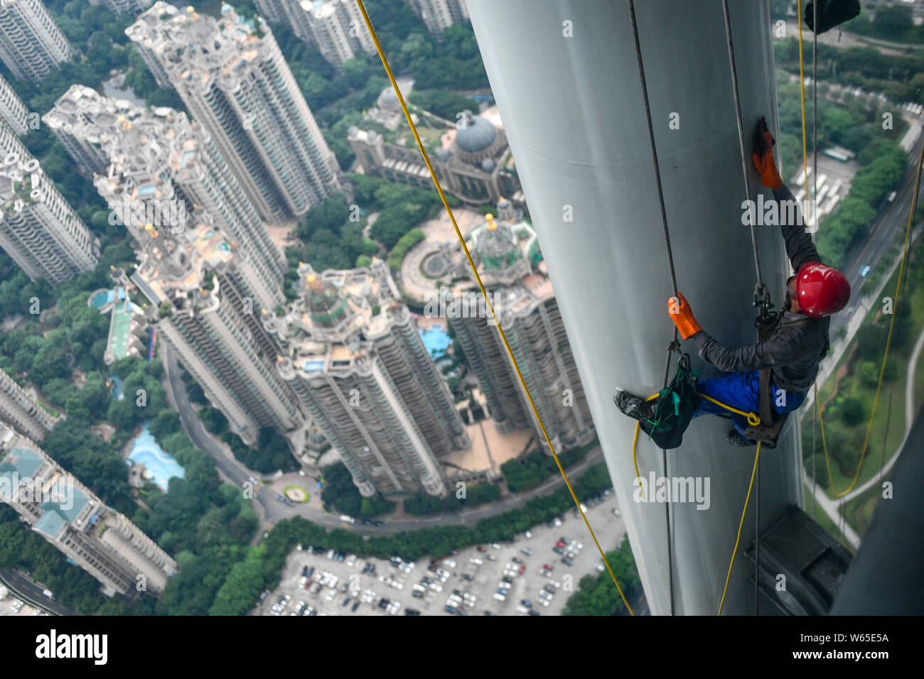 Ein chinesischer Wanderarbeiter baumelt an einem Seil im Kanton oder Guangzhou Turm Turm während der Gewitter in der Stadt Guangzhou zu reinigen, der South China Gua Stockfoto