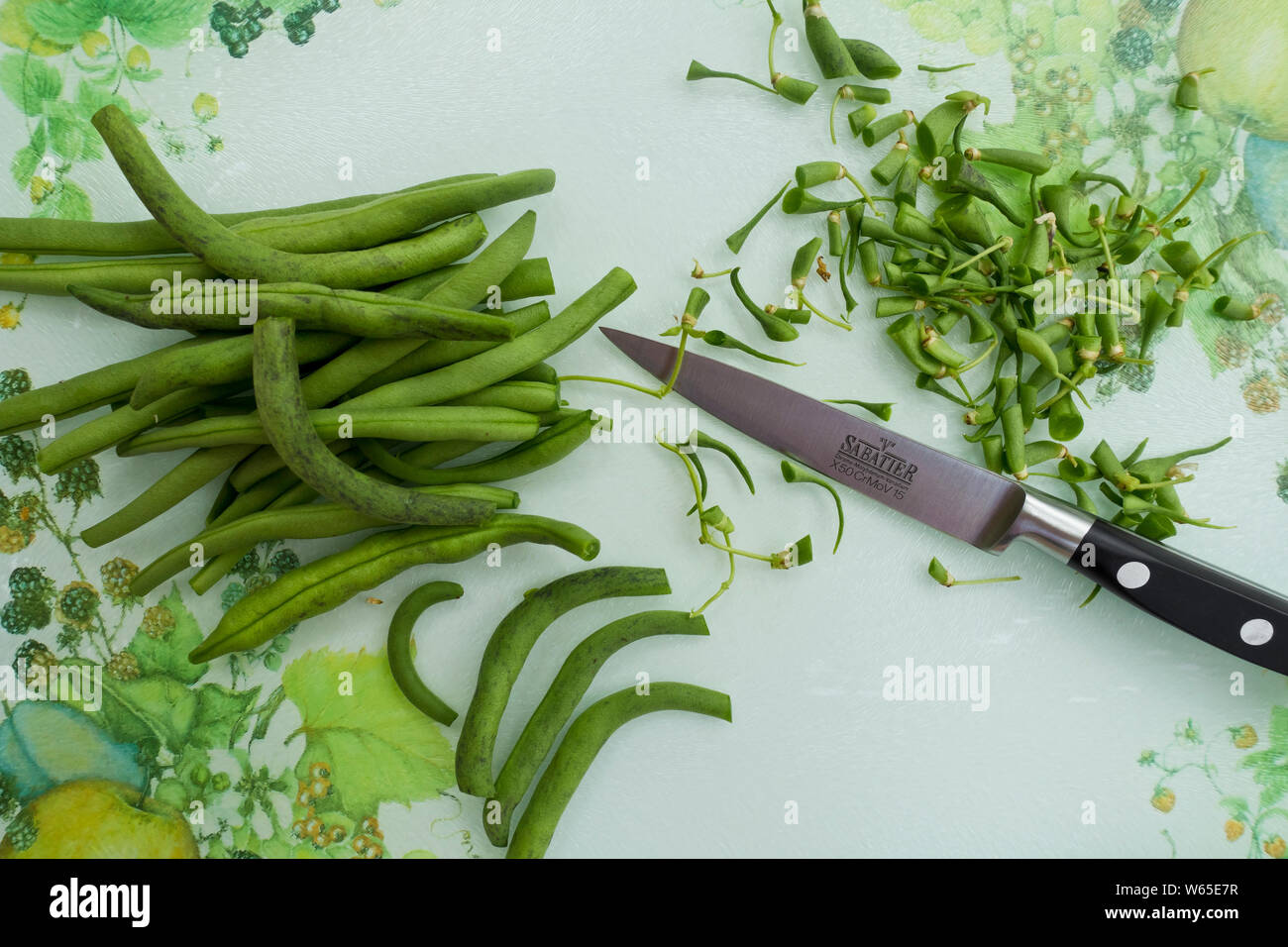Nahaufnahme von gehackten rohen grünen Laufbohnen Gemüse Gemüse Gemüse Gemüse in einer Küche bereit zum Kochen mit einem Messer und Schneidebrett Stockfoto