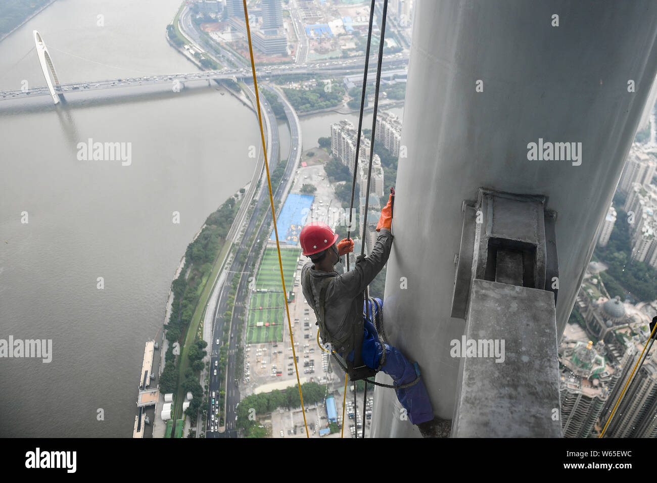 Ein chinesischer Wanderarbeiter baumelt an einem Seil im Kanton oder Guangzhou Turm Turm während der Gewitter in der Stadt Guangzhou zu reinigen, der South China Gua Stockfoto