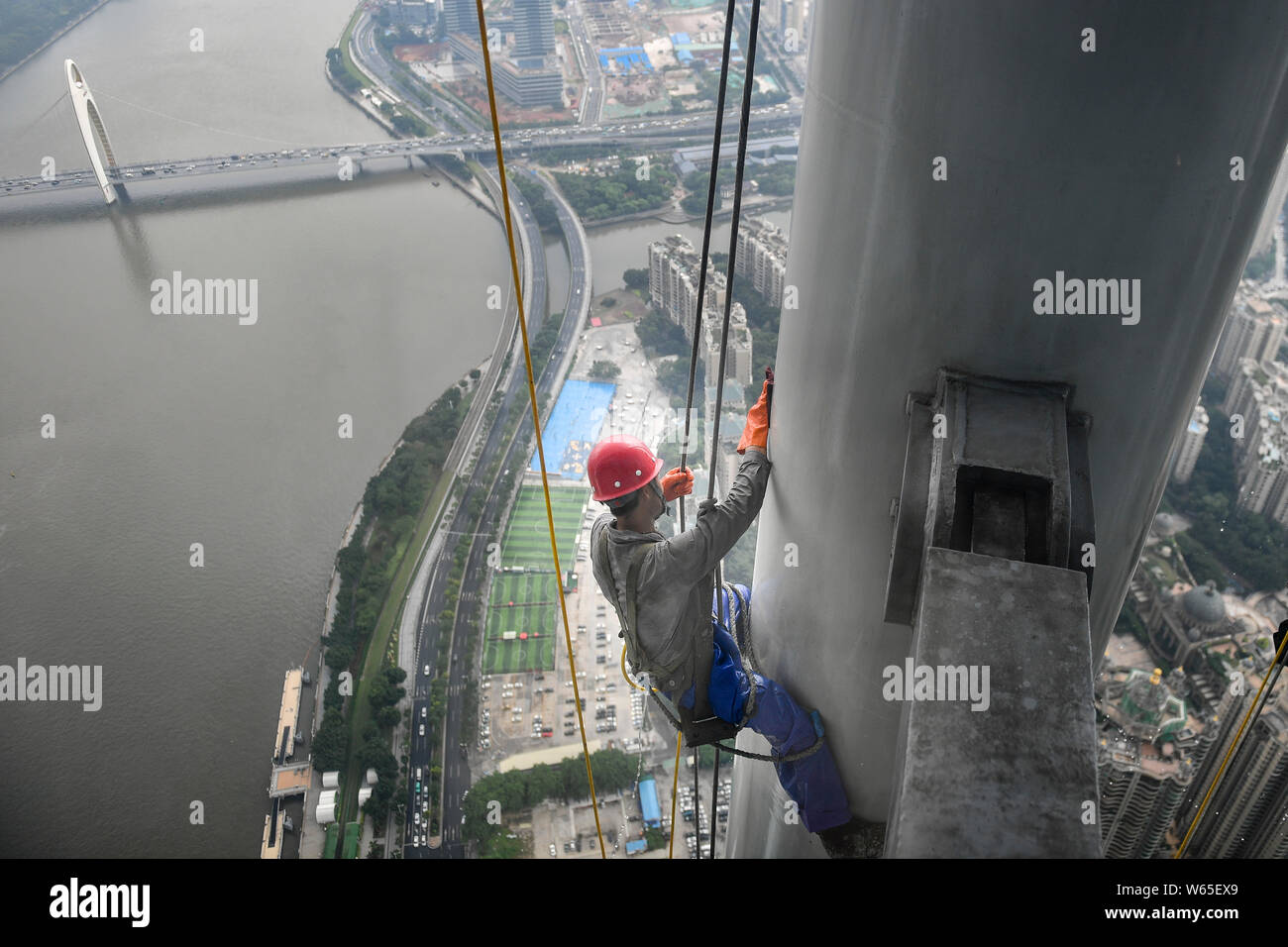 Ein chinesischer Wanderarbeiter baumelt an einem Seil im Kanton oder Guangzhou Turm Turm während der Gewitter in der Stadt Guangzhou zu reinigen, der South China Gua Stockfoto