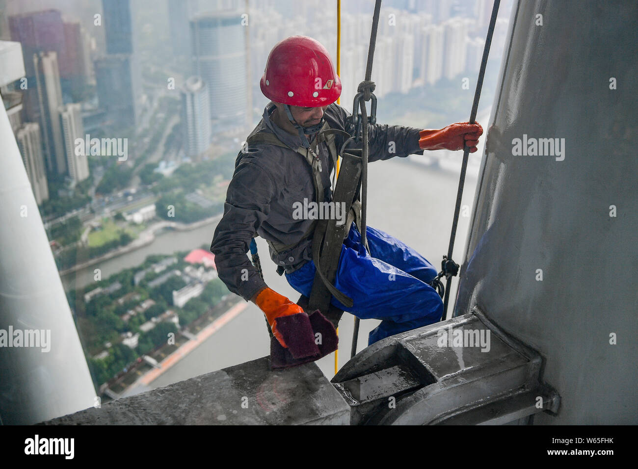 Ein chinesischer Wanderarbeiter baumelt an einem Seil im Kanton oder Guangzhou Turm Turm während der Gewitter in der Stadt Guangzhou zu reinigen, der South China Gua Stockfoto