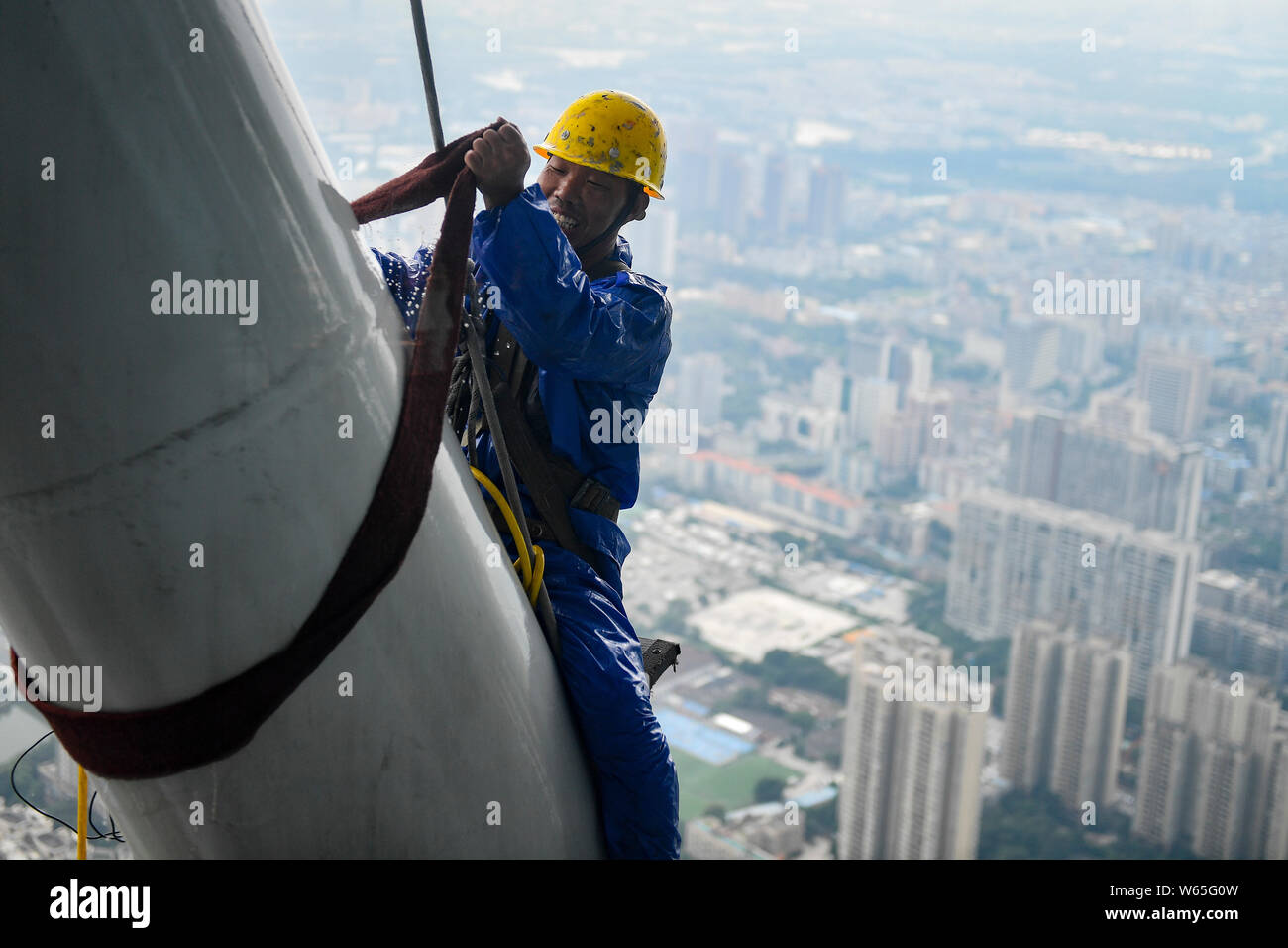 Ein chinesischer Wanderarbeiter baumelt an einem Seil im Kanton oder Guangzhou Turm Turm während der Gewitter in der Stadt Guangzhou zu reinigen, der South China Gua Stockfoto