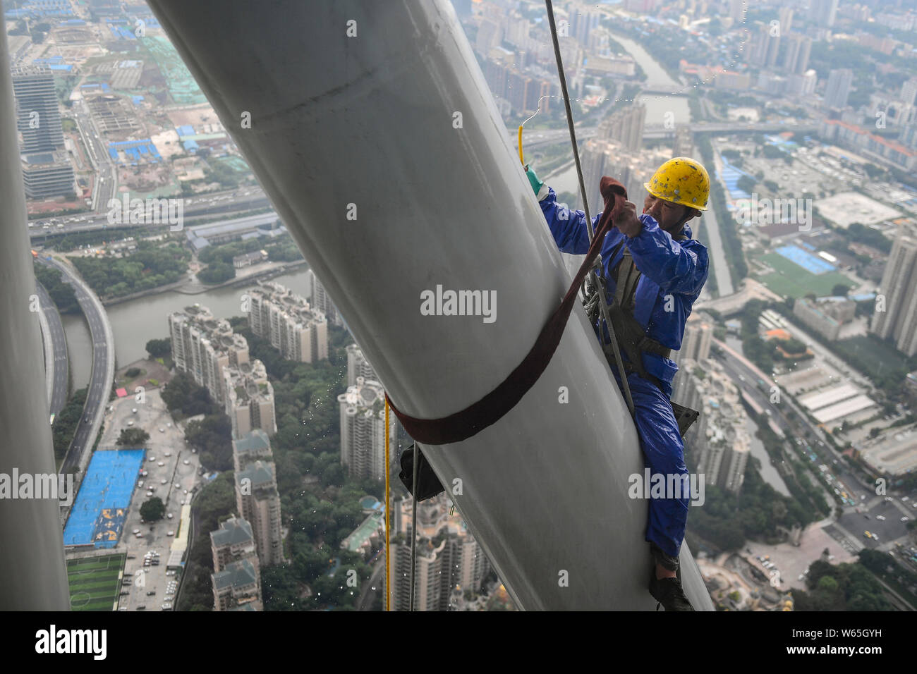 Ein chinesischer Wanderarbeiter baumelt an einem Seil im Kanton oder Guangzhou Turm Turm während der Gewitter in der Stadt Guangzhou zu reinigen, der South China Gua Stockfoto