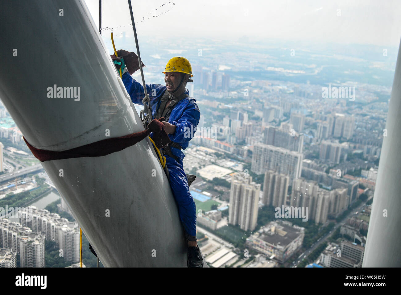 Ein chinesischer Wanderarbeiter baumelt an einem Seil im Kanton oder Guangzhou Turm Turm während der Gewitter in der Stadt Guangzhou zu reinigen, der South China Gua Stockfoto