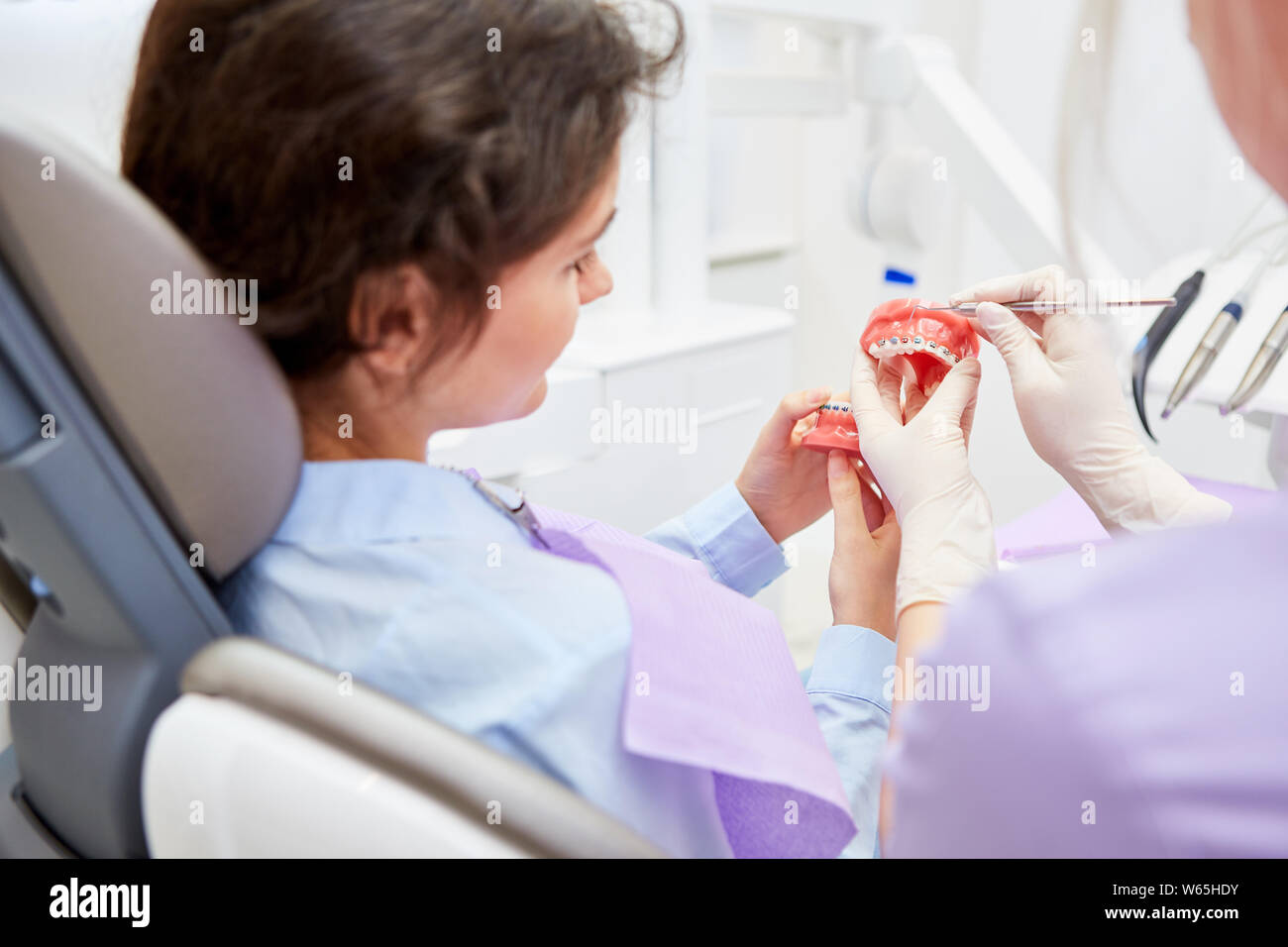 Zahnarzt oder Zahnarzthelfer erklärt die Wirkung der geschweiften Klammern oder Klammern auf dem Modell Stockfoto