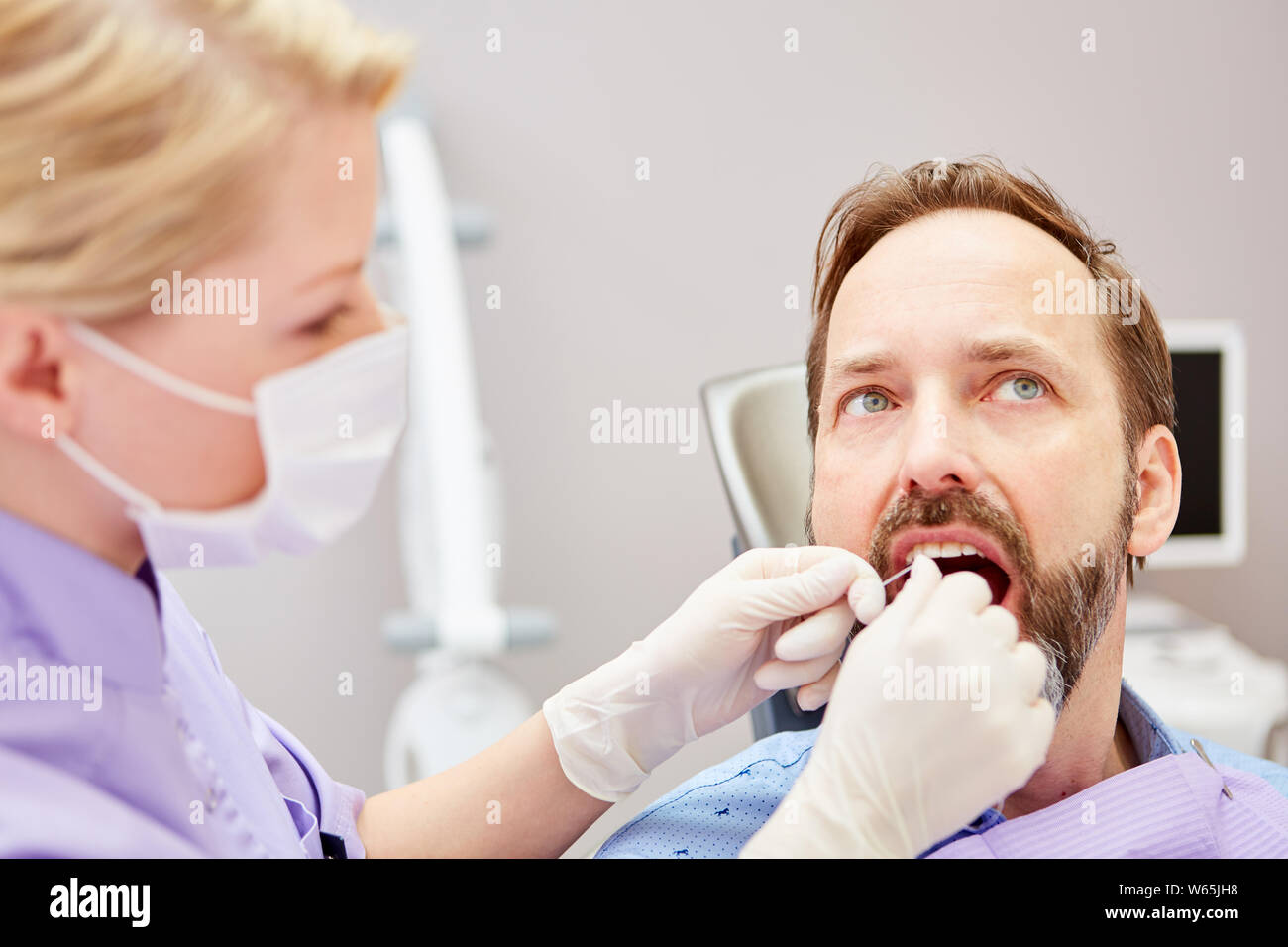 Zahnarzthelfer bildet das Flossing eine professionelle Zahnreinigung bei einem Patienten Stockfoto