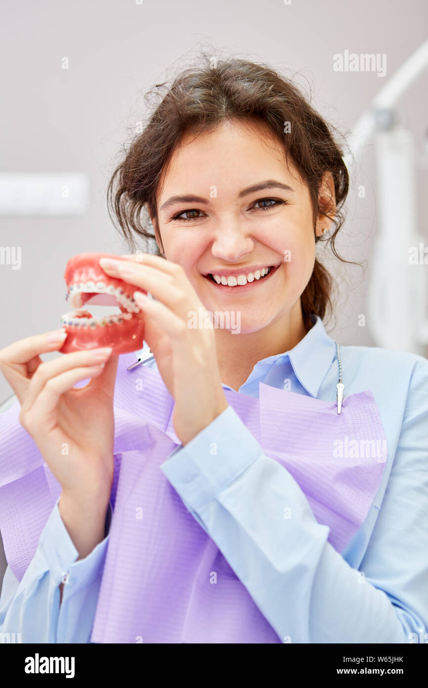 Fröhliche Frau als Patient mit Zahnersatz Modell mit Klammern eine Fehlstellung zu korrigieren. Stockfoto