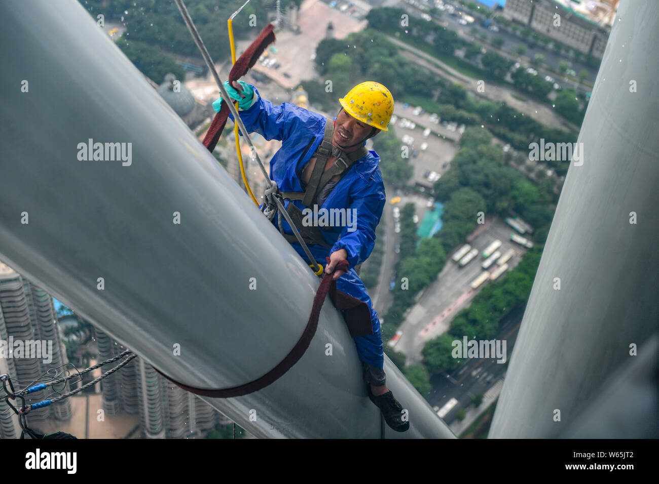 Ein chinesischer Wanderarbeiter baumelt an einem Seil im Kanton oder Guangzhou Turm Turm während der Gewitter in der Stadt Guangzhou zu reinigen, der South China Gua Stockfoto