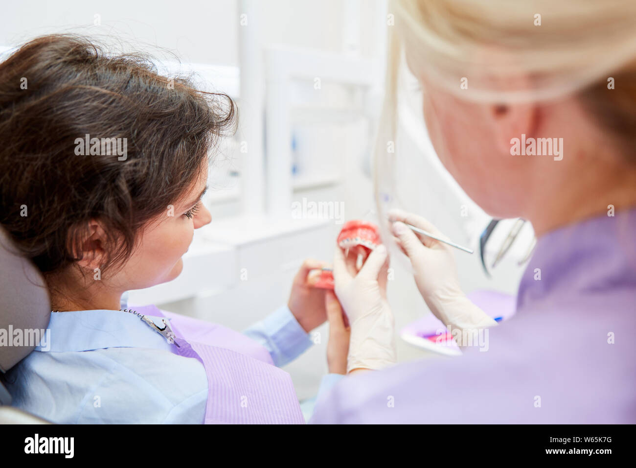 Kieferorthopäde erklärt einem Patienten die Wirkung der zahnmedizinischen Klammer auf eine Prothese Modell Stockfoto
