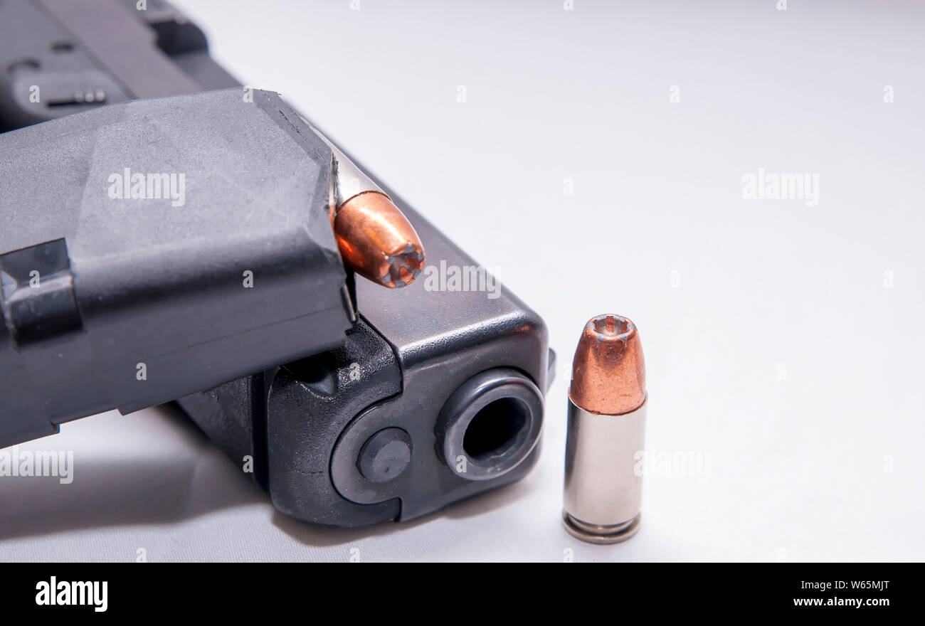 Ein schwarzes 9-mm-Pistole mit einer geladenen Magazin auf Sie und einer einzigen 9 mm Hollow point bullet Weiter, um es auf einem weißen Hintergrund Stockfoto