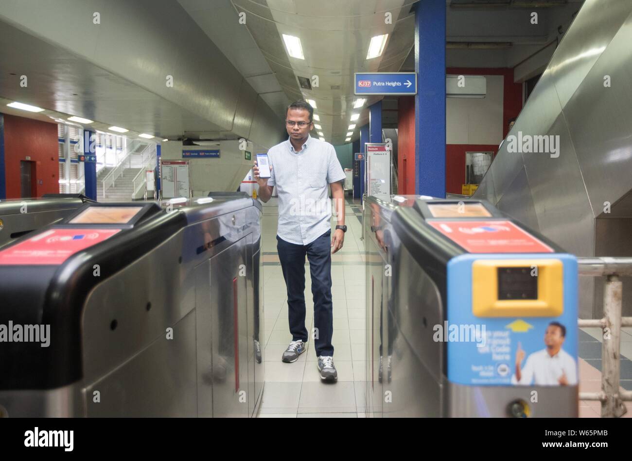 ---- Ein pendler setzt sein Smartphone über ein Drehkreuz der QR-Code über das mobile e-wallet Payment Service Touch & Go von TNG Digitale betrieben zu haben Stockfoto