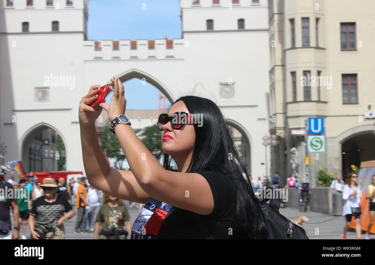 Stilbewusste Frauen touristische funktioniert ein selfie in München Stadt. Das karlstor in der backgroundt Stockfoto