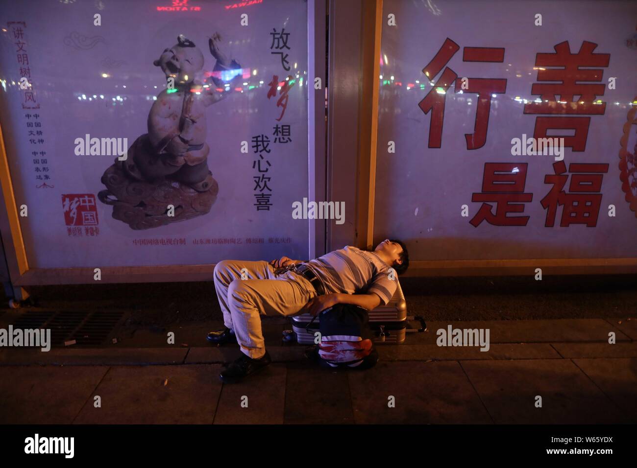 Einen chinesischen Pkw schläft und wartet auf seinen Zug auf dem Platz der Beijing Railway Station in Peking, China, 18. August 2018. Chinesische Passagiere sl Stockfoto