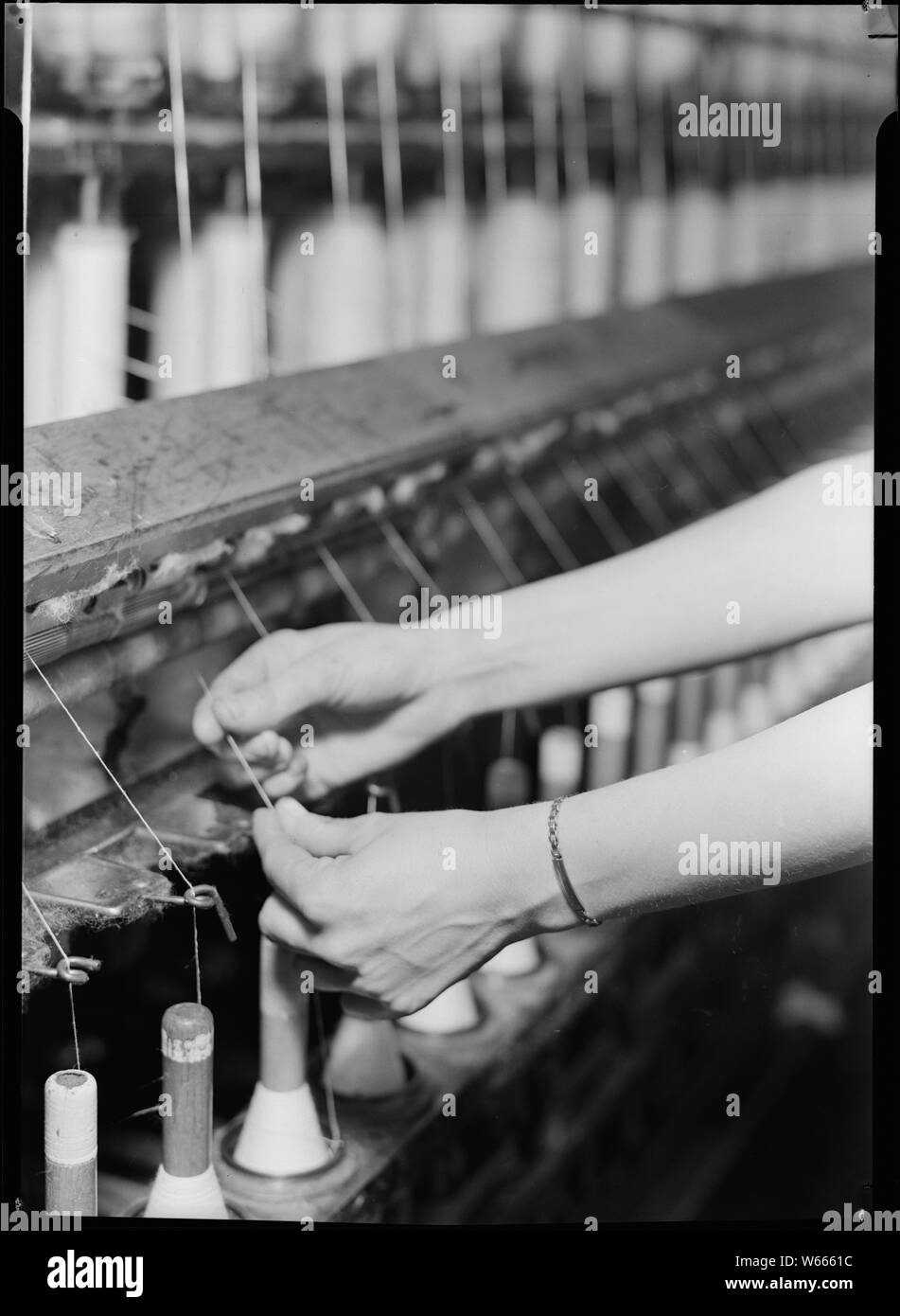 High Point, North Carolina- Textilien. Pickett Garn Mill. Spinning - Saco-Lowell Maschine - sie zeigen die Hände der Frau in Betrieb - Hoch qualifizierte Stockfoto