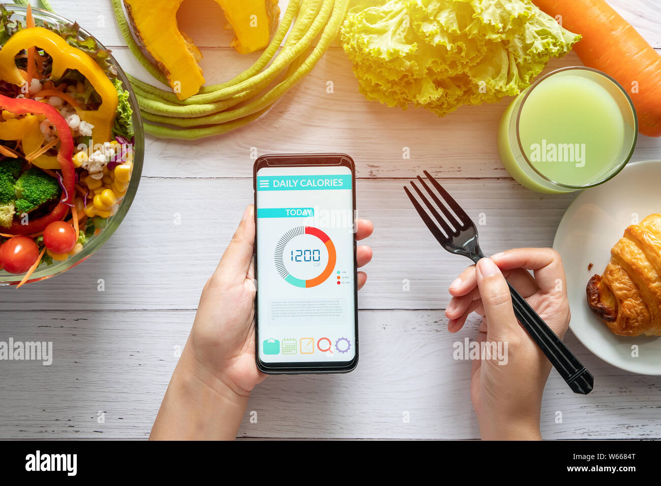 Kalorien zählen, Ernährung, der Kontrolle und Gewichtsverlust Konzept. Frau mit Kalorienzähler Anwendung auf Ihrem Smartphone am Esstisch mit Salat, Stockfoto