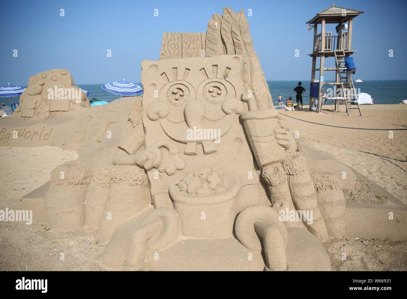 Ein Sand Skulptur von Zeichen aus pongeBob des Amerikanischen animierte TV-Serie "SCHWAMMKOPF" ist auf dem Display auf einem Strand in Rizhao, East China Sh Stockfoto