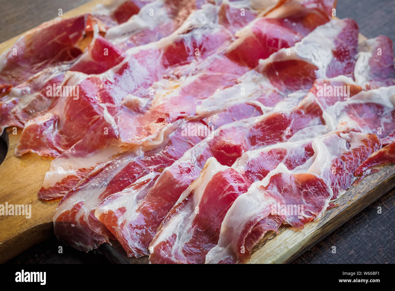 Iberico Schinken schneiden auf einem Holzbrett, spanisch typische Tapa Stockfoto