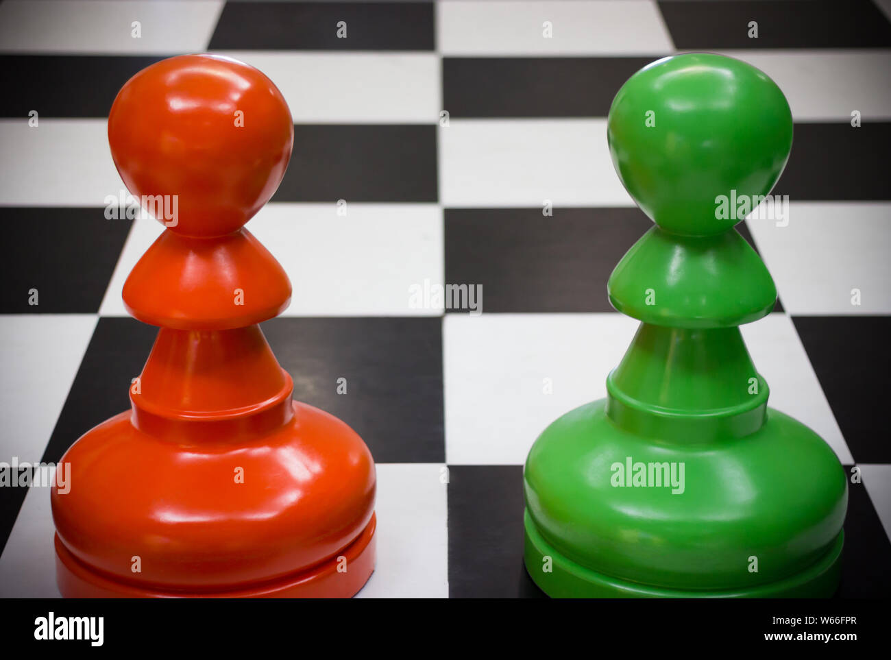 Grüne Spielfigur und Rote Spielfigur konfrontieren auf Schachbrett Stockfoto