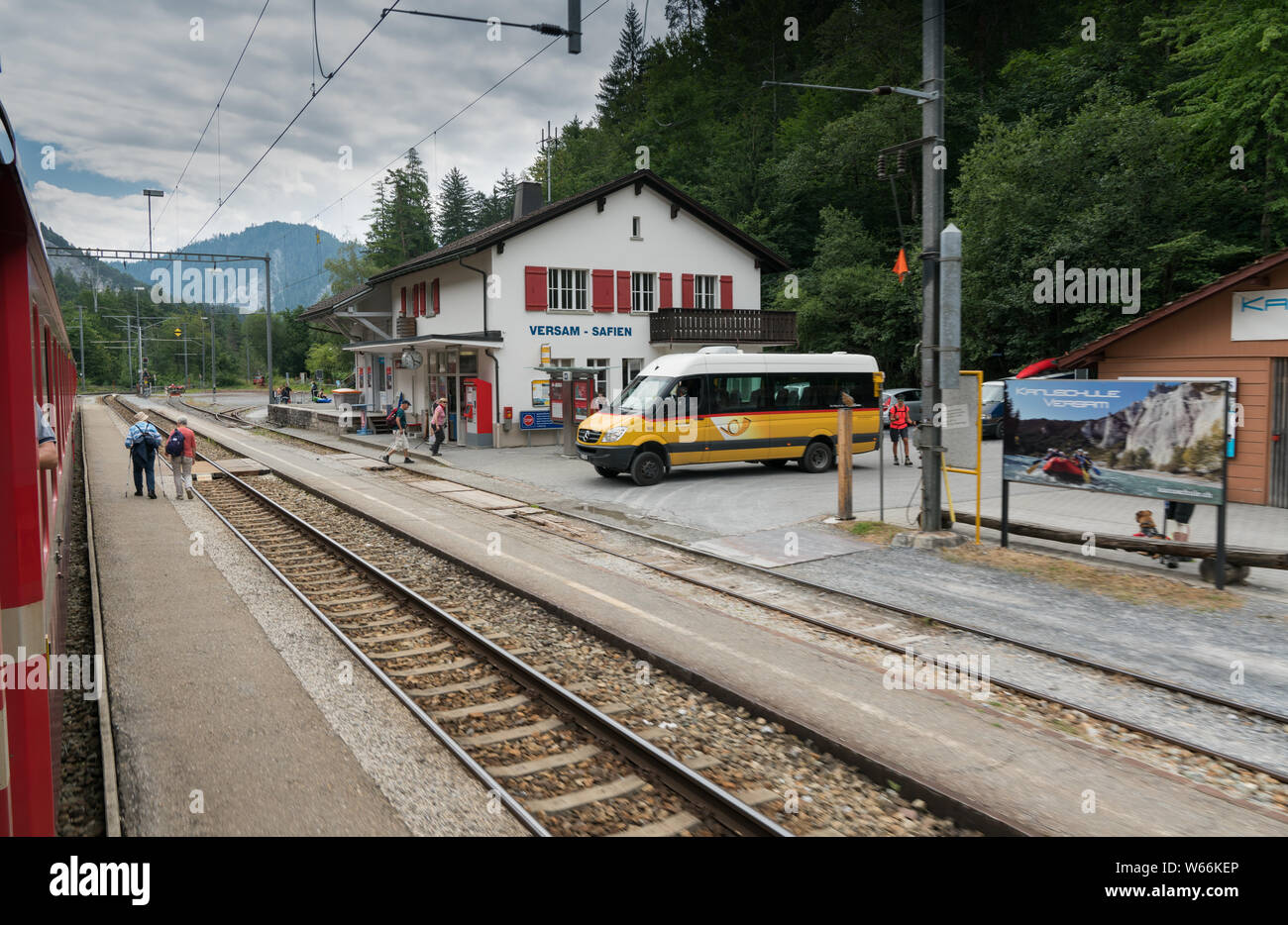 Versam, GR/Schweiz - 30. Juli 2019: öffentliche Bus wartet am Bahnhof in Versam für den Zug zu passieren, während viele Touristen zu Fuß Stockfoto