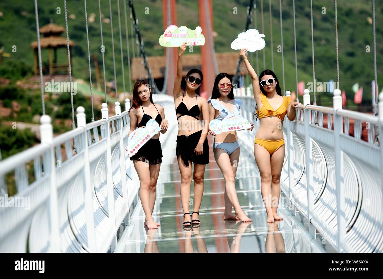 Chinesische Schönheiten im Bikini stellen auf der 5D Glas Brücke an das WAN eine Shan Grand Canyon in Luoyang City, Central China Provinz Henan, 21. Juli 2018. Stockfoto