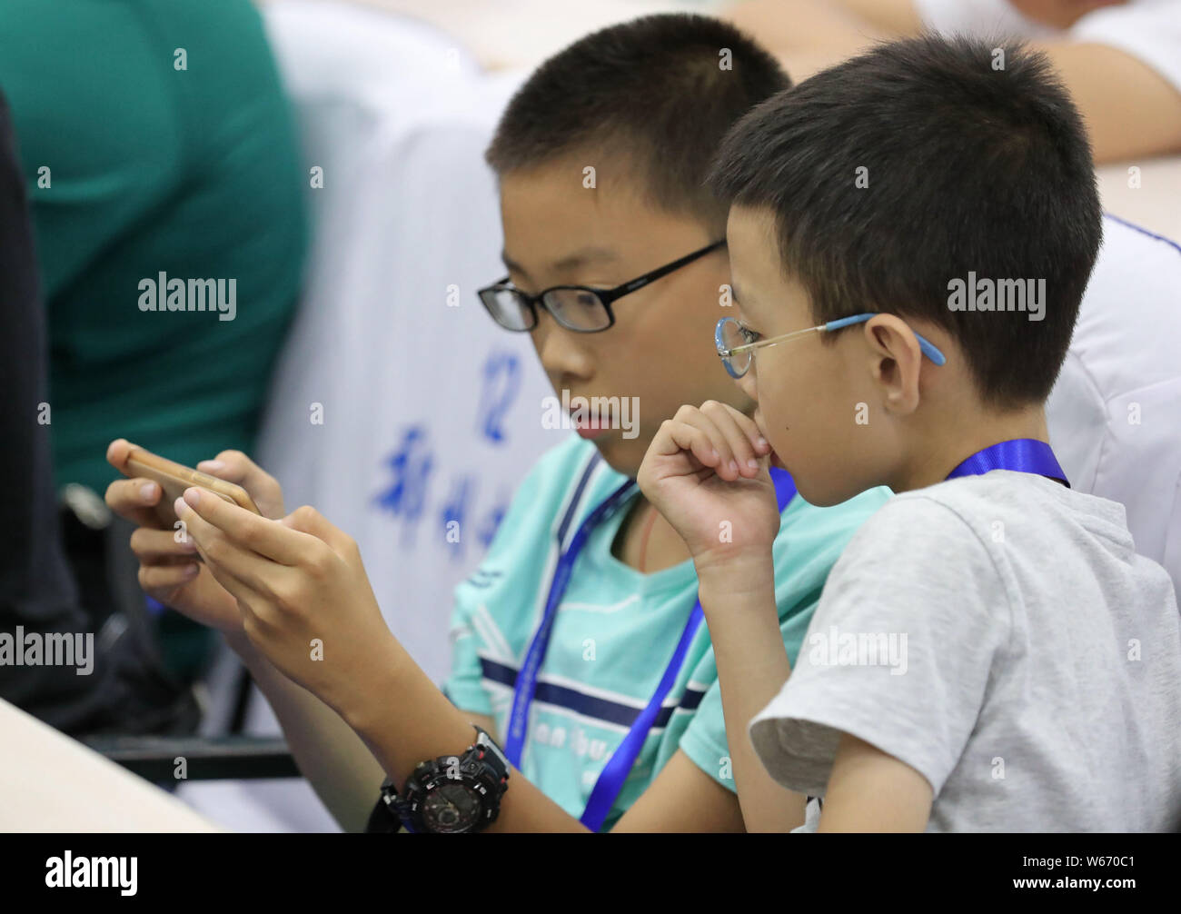 ---- Kurzsichtige Kinder tragen Brillen Videospiele auf ein Smartphone in Zhengzhou City spielen, der Central China Provinz Henan, 17. Juli 2018. Ein Stockfoto