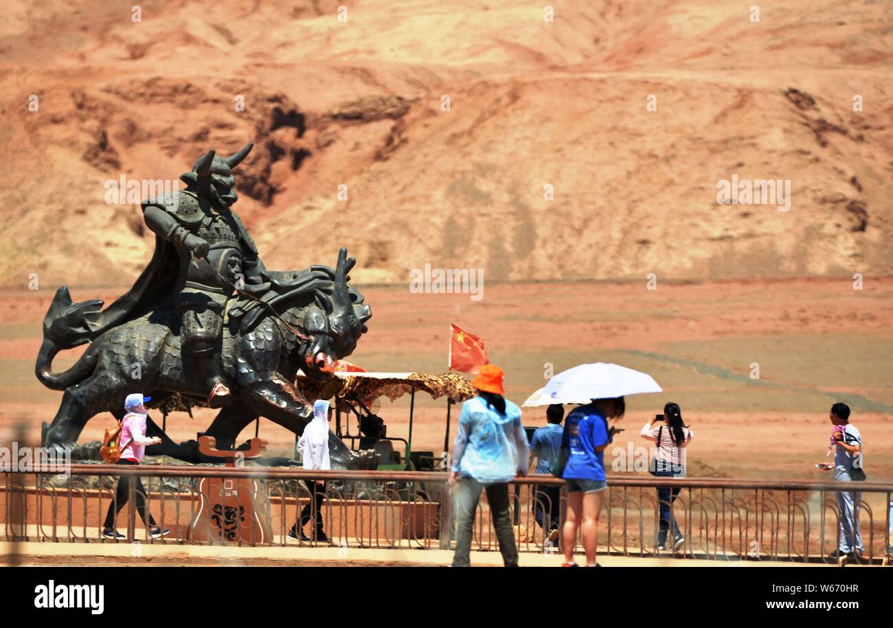 Touristen posieren für Fotos mit den Sehenswürdigkeiten Skulptur am Fuße des Huoyan (Flaming) Berg in Turpan Becken, im Nordwesten Chinas Xinjiang Uygur au Stockfoto