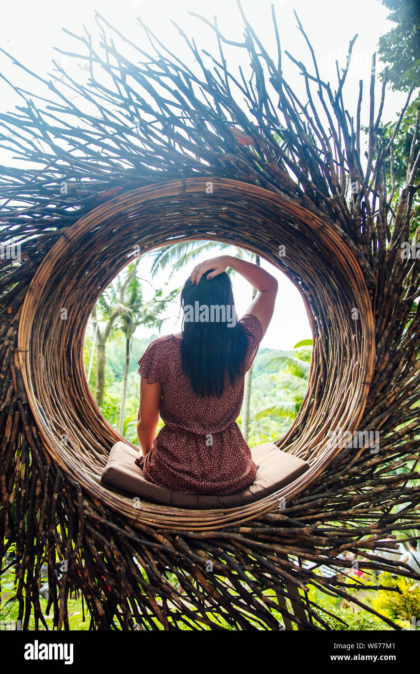 Eine weibliche Touristen sitzen auf einem großen Vogelnest auf einem Baum an der Insel Bali, Indonesien Stockfoto