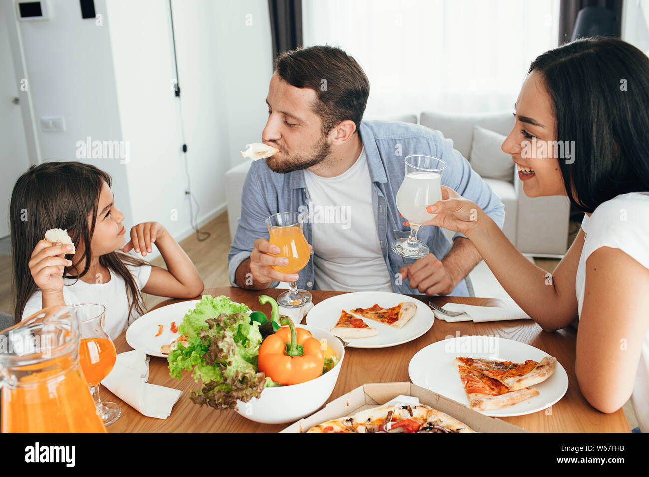 Glücklich, multi-ethnische Familie, Mutter, Vater und Tochter beim Abendessen. Das Essen lecker Pizza mit Familie Stockfoto