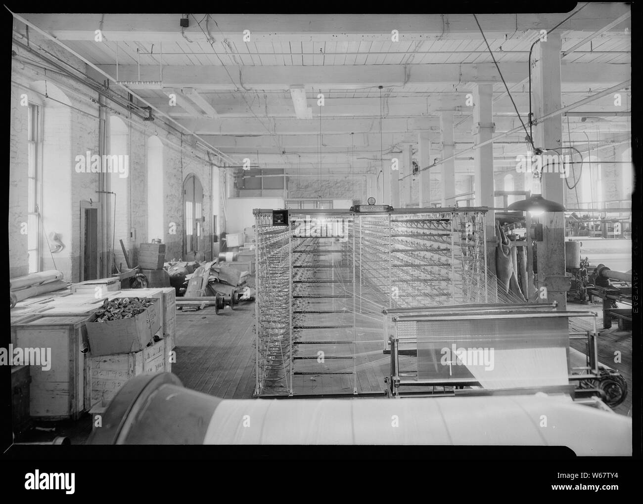 Paterson, New Jersey - Textilien. Jackson Wicklung und Verziehen. Bild von einem Sipp-Eastwood DY Art der High Speed Warper. Diese Maschine ist ähnlich wie oben, außer dass die Verwerfung auf die alte Art von creel gewickelt ist. Nach dem Warp ist es strahlte. Auf diese Art von Maschine dauert es 2-1/4 bis 2-1/2 Stunden das übliche Art der Verwerfung zu machen. Diese Schätzung der Zeit können variieren leicht die eine oder andere Weise, je nach der Anzahl der Abschnitte, Länge der Verwerfung, etc. Deutsch: English: Conusschärmaschine Conusscheermachine Stockfoto