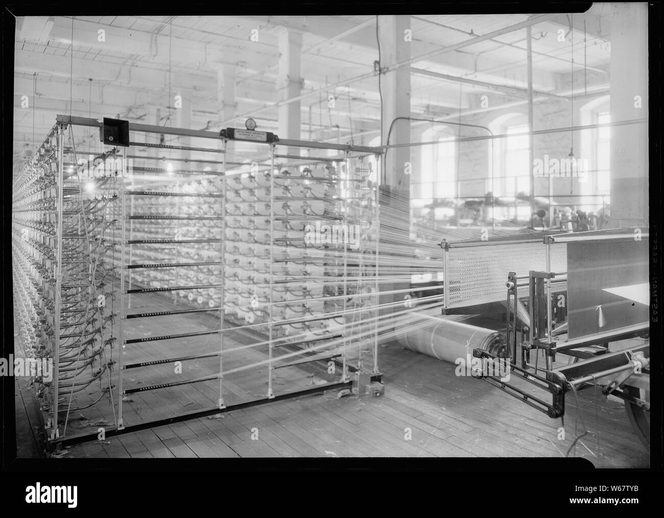 Paterson, New Jersey - Textilien. Jackson Wicklung und Verziehen. Bild von einem Sipp-Eastwood DY Art der High Speed Warper. Diese Maschine ist ähnlich wie oben, außer dass die Verwerfung auf die alte Art von creel gewickelt ist. Nach dem Warp ist es strahlte. Auf diese Art von Maschine dauert es 2-1/4 bis 2-1/2 Stunden das übliche Art der Verwerfung zu machen. Diese Schätzung der Zeit kann leicht auf so oder so, je nach Anzahl der Abschnitte, Länge der Kette variieren. Stockfoto