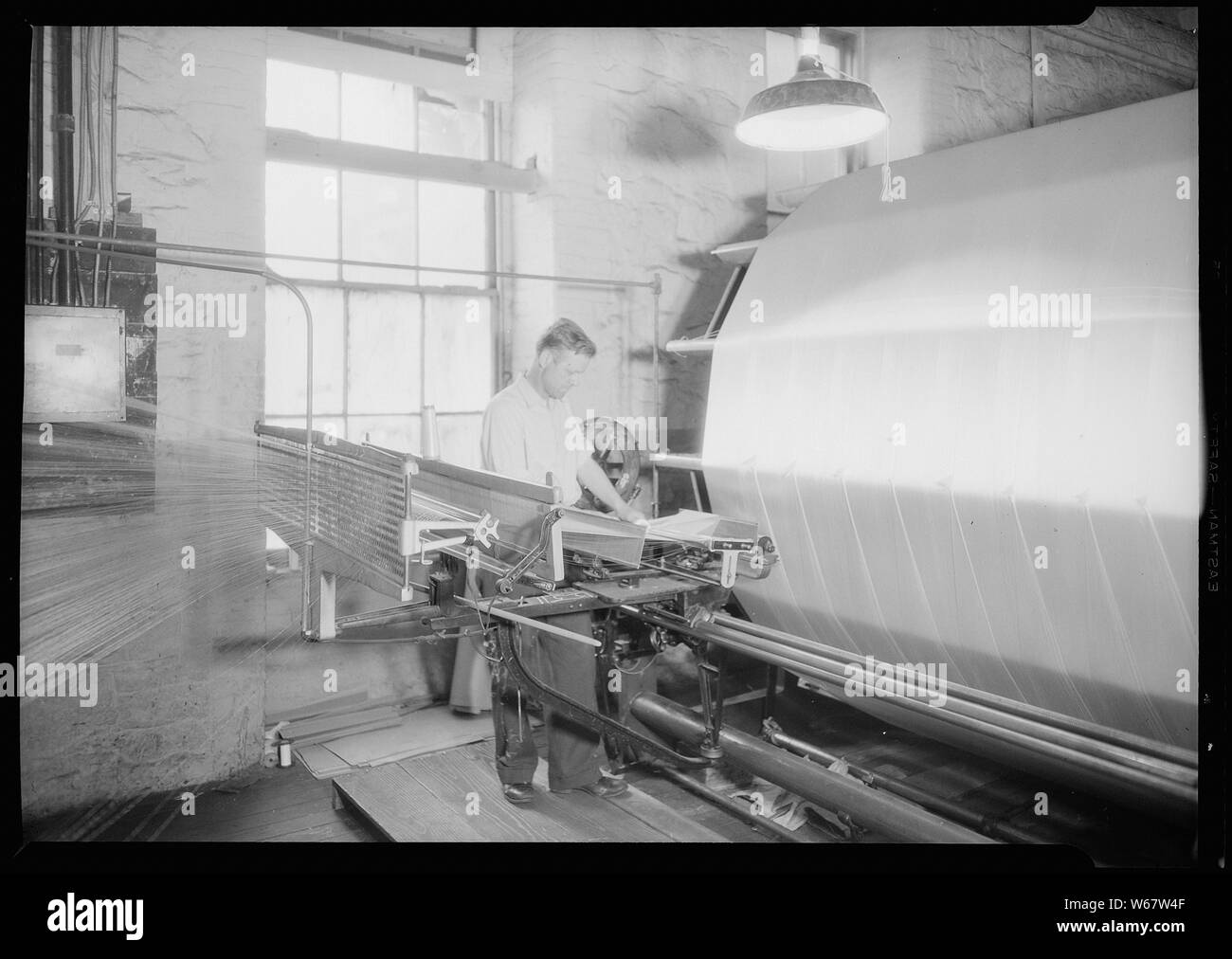 Paterson, New Jersey - Textilien. Jackson Wicklung und Verziehen. Bild von einem Sipp-Eastwood DY Art der High Speed Warper. Diese Maschine ist ähnlich wie oben, außer dass die Verwerfung auf die alte Art von creel gewickelt ist. Nach dem Warp ist es strahlte. Auf diese Art von Maschine dauert es 2-1/4 bis 2-1/2 Stunden das übliche Art der Verwerfung zu machen. Diese Schätzung der Zeit können variieren leicht die eine oder andere Weise, je nach der Anzahl der Abschnitte, Länge der Verwerfung, etc. Deutsch: Scheermachine met Unterstützung English: Schärmaschine Stockfoto